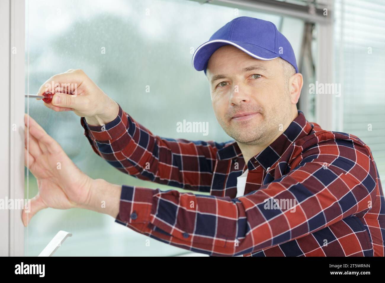 worker fasten the handle to a plastic window Stock Photo