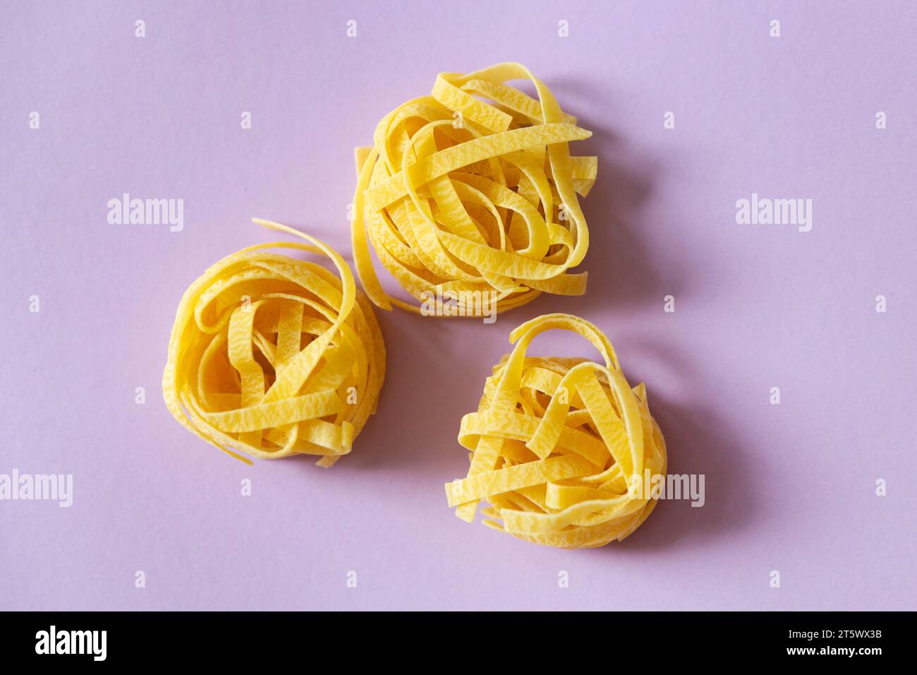 Sphagetti tagliatelle pasta on the pink background Stock Photo