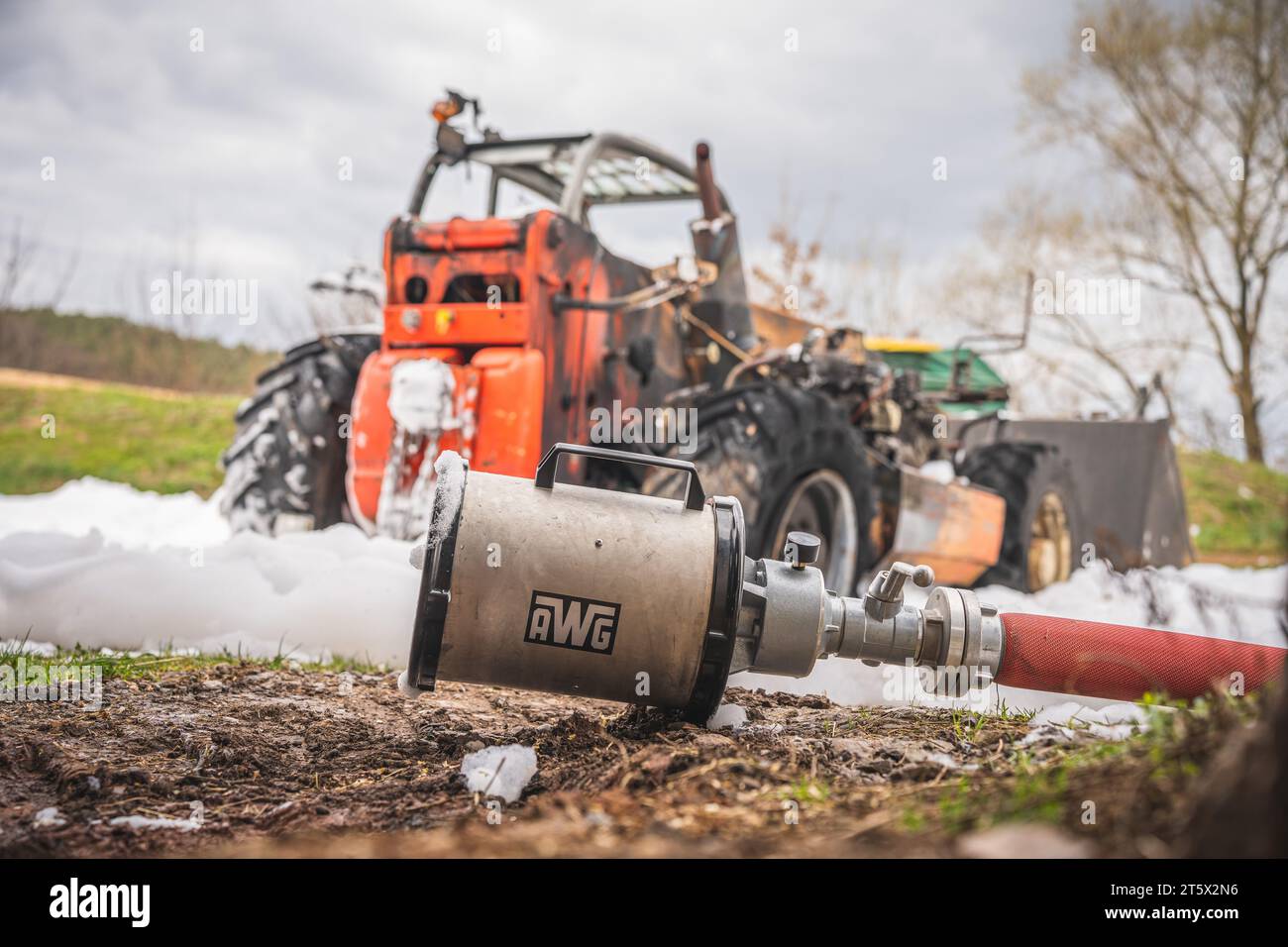 Ein Schaumrohr der Feuerwehr liegt nach der Verwendung bei einem Radladerbrand bereit.  Ein Schaumteppich ist am Boden zu sehen.  28.03.2023 Stock Photo