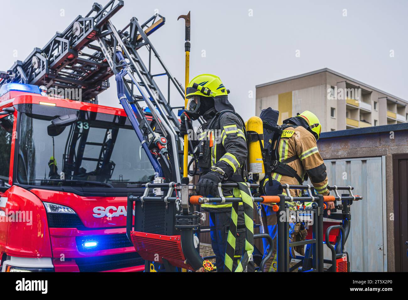 Zwei Einsatzkräfte der Feuerwehr, ausgerüstet mit Einreishaken und schwerem Atemschutz, bereit zum Einsatz im Korb einer Drehleiter.  18.04.2023 Stock Photo