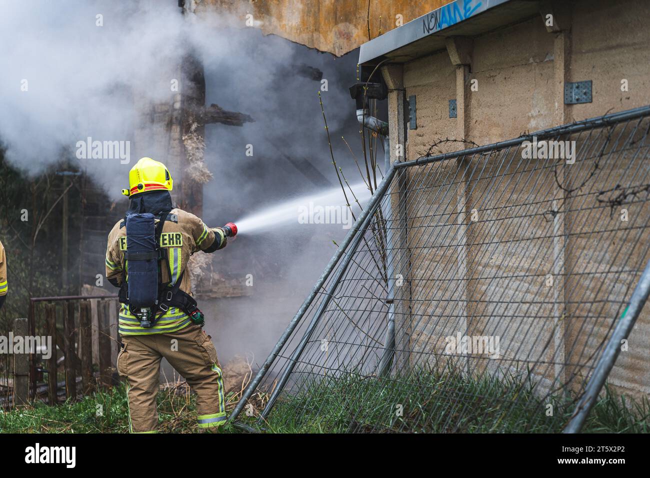 Ein Feuerwehrmann unter Atemschutz löscht einen Wohnhausbrand von außen.  18.04.2023 Stock Photo