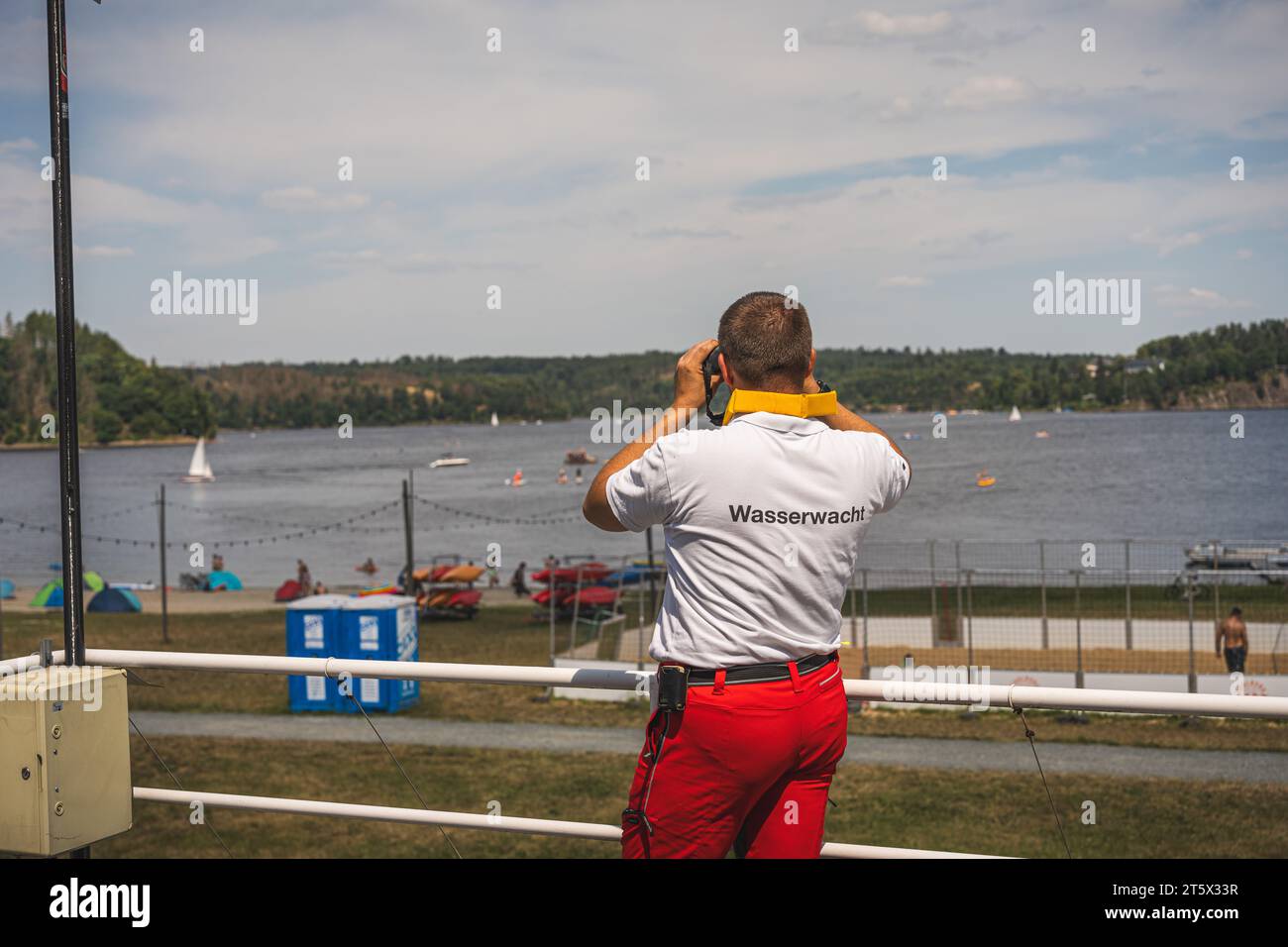 Eine Einsatzkraft der Wasserwacht überwacht den Badestrand mit einem Fernglas.  08.07.2023 Stock Photo