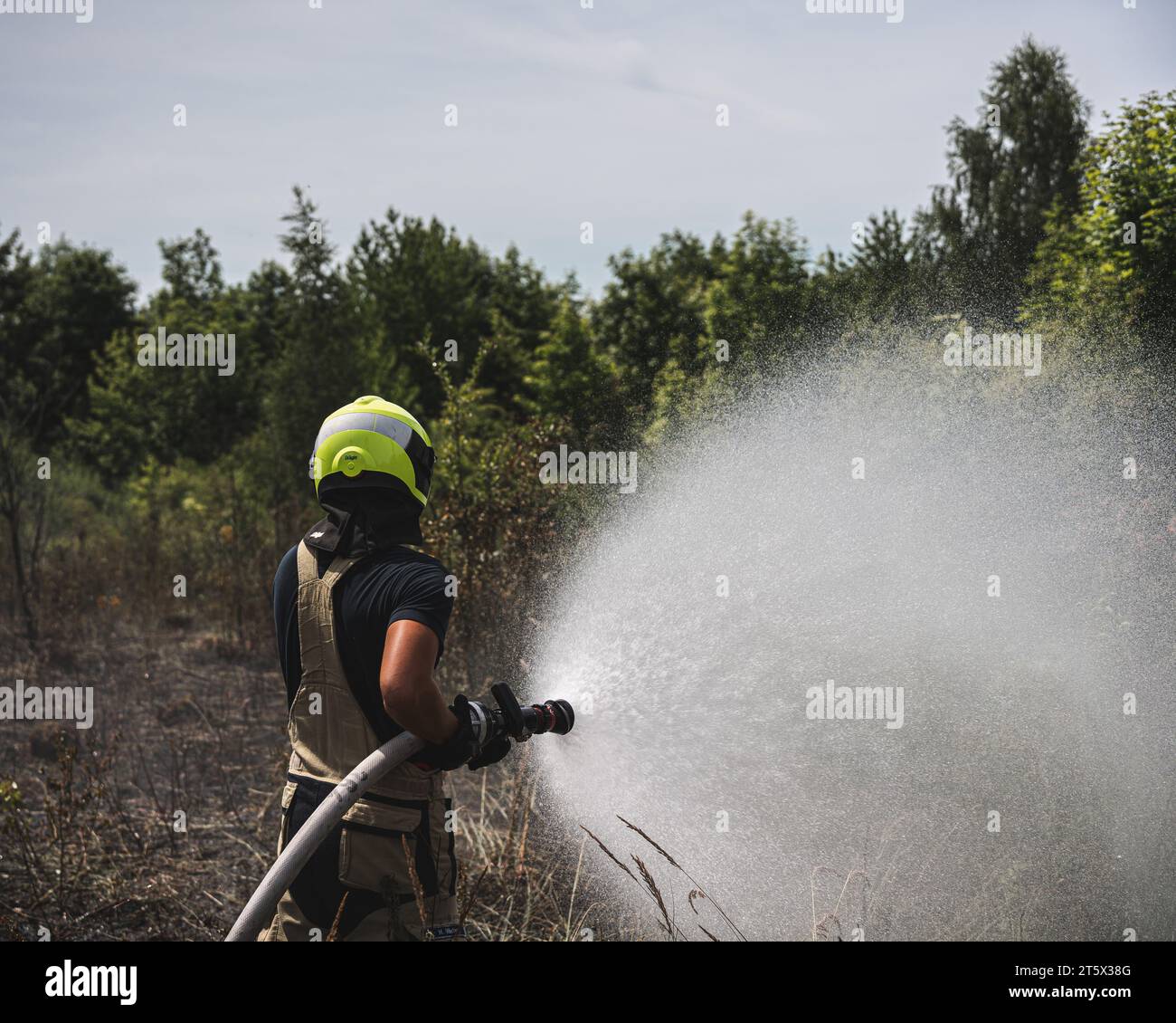 Ein Feuerwehrmann bekämpft einen Feldbrand mit Wasser.  Am 18.07.2022 Stock Photo