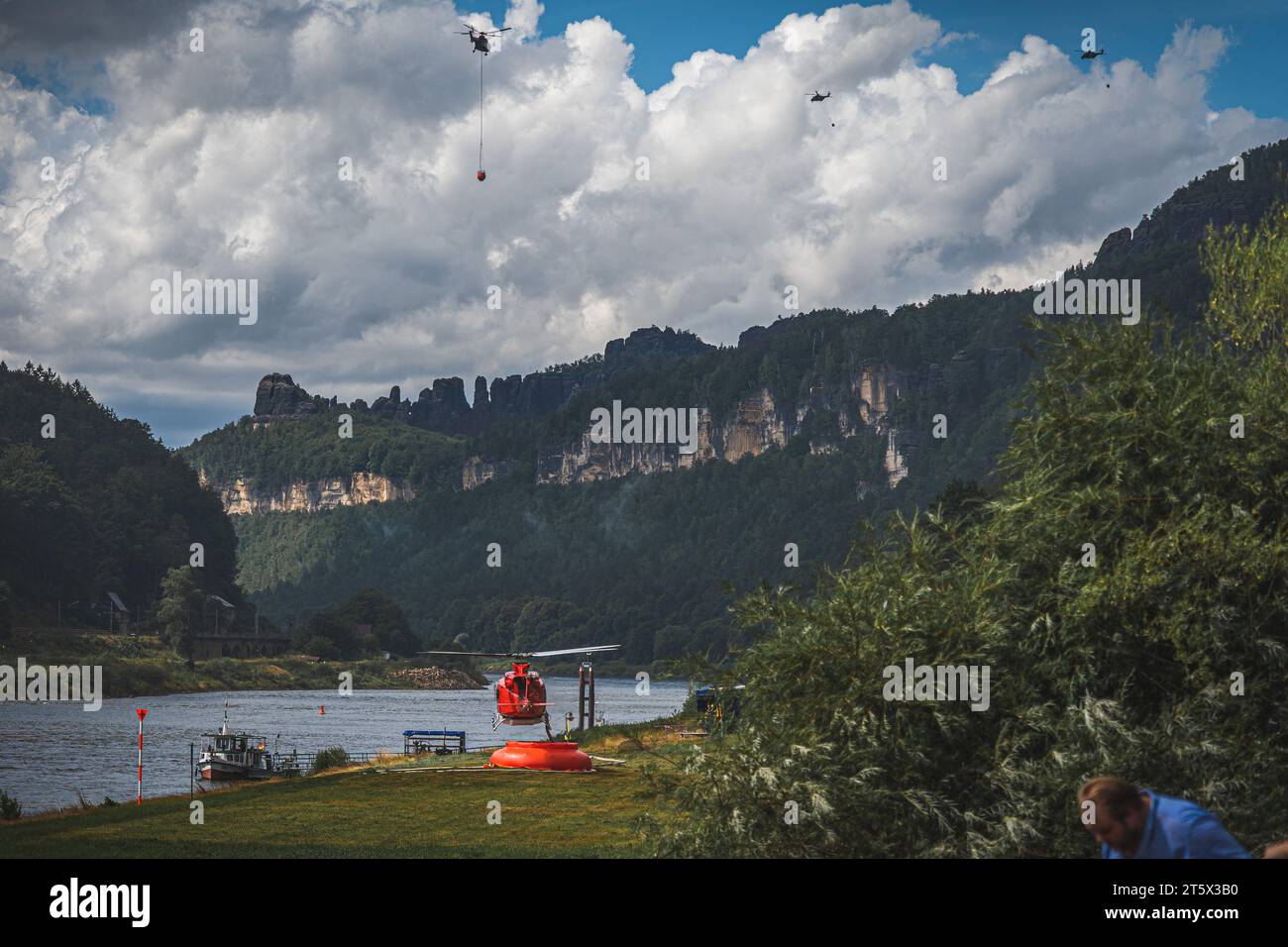 Ein Hubschrauber befüllt seinen Tank um bei den Löscharbeiten von Waldbränden zu unterstützen.  Im Hintergrund sind weitere Hubschrauber mit Löschwass Stock Photo