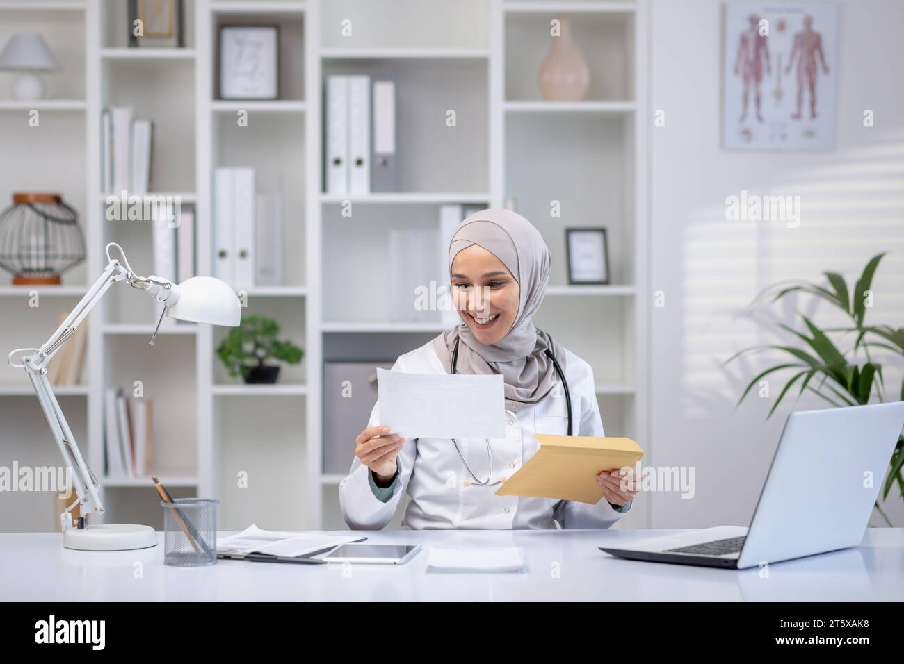 Joyful female doctor in hijab received envelope message mail ...