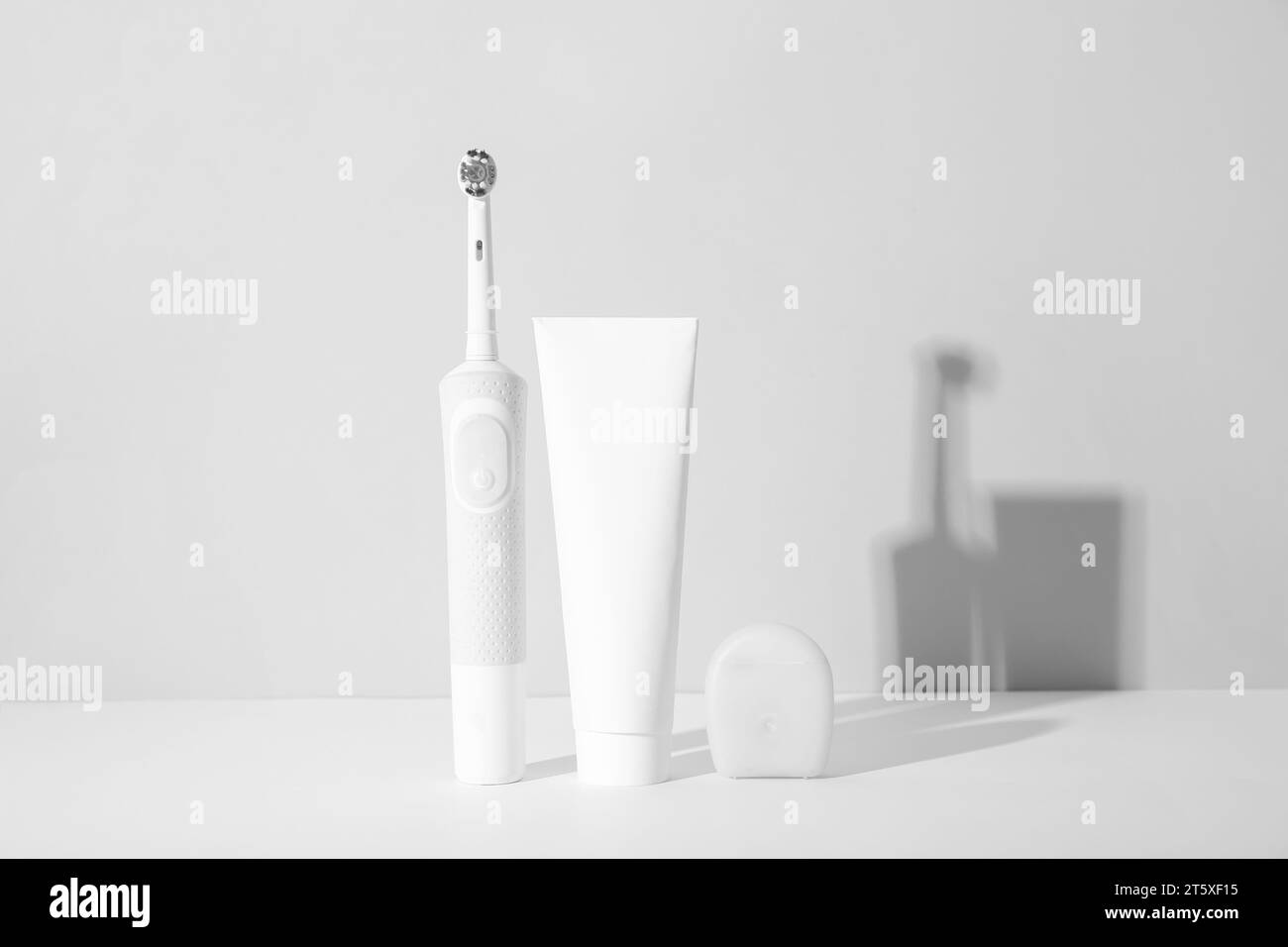 Electric toothbrush with toothpaste and dental floss on white