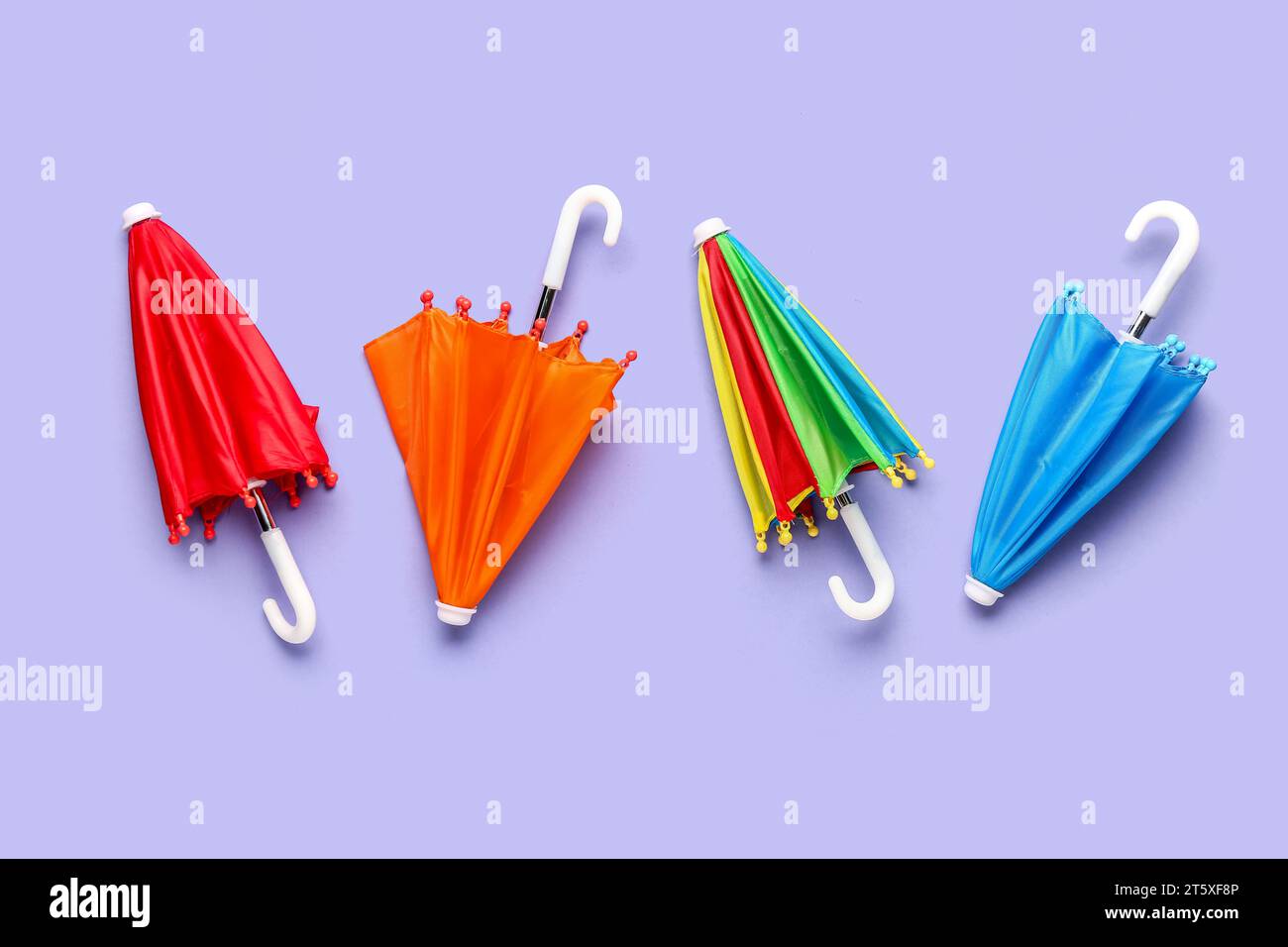 Mini stylish umbrellas on lilac background Stock Photo