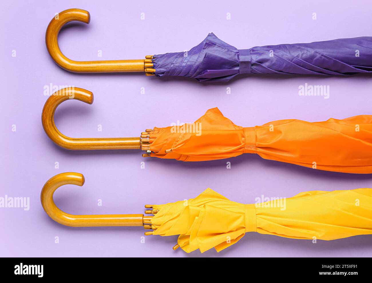 Different stylish umbrellas on lilac background Stock Photo