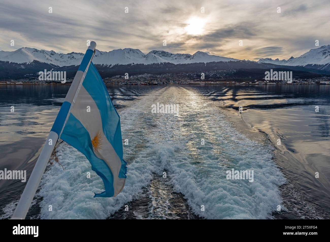 Sunset over Ushuaia city seen from Beagle Channel Boat excursion with argentinian flag, Argentina. Stock Photo