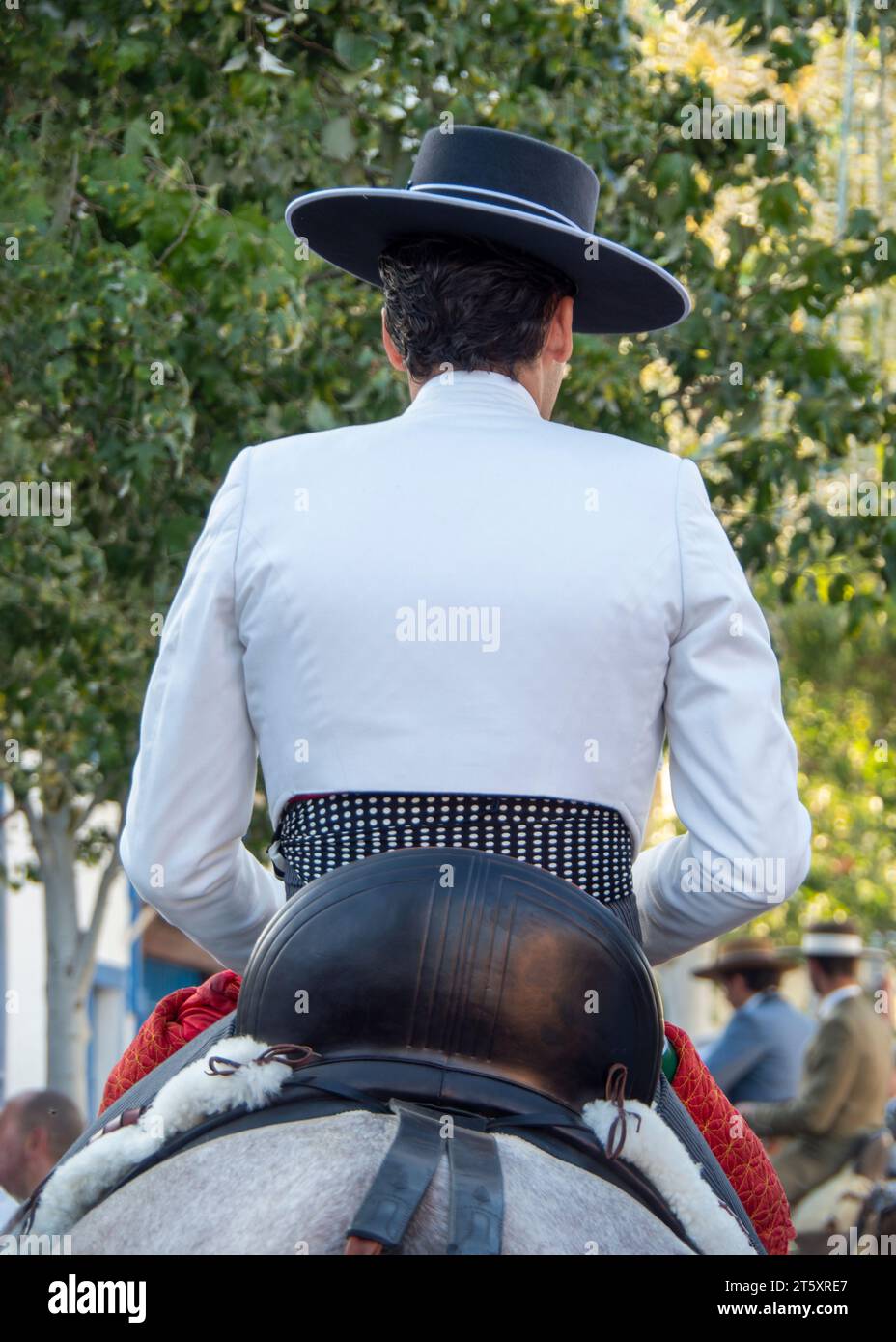 Groups of horse riders dressed in typical Andalusian costume, riding through the fairgrounds of Fuengirola during the celebration of the Feria Stock Photo