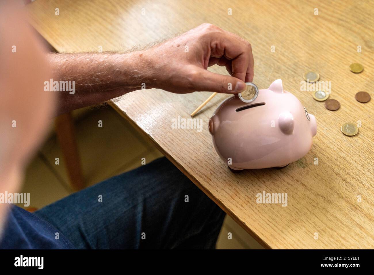 Augsburg, Bayern, Deutschland - 27 Oktober 2023: Ein alter Mann wirft Euro Geldmünzen in ein Sparschwein. Altersvorsorge Konzept *** An old man throws euro coins into a piggy bank. Retirement provision concept Credit: Imago/Alamy Live News Stock Photo