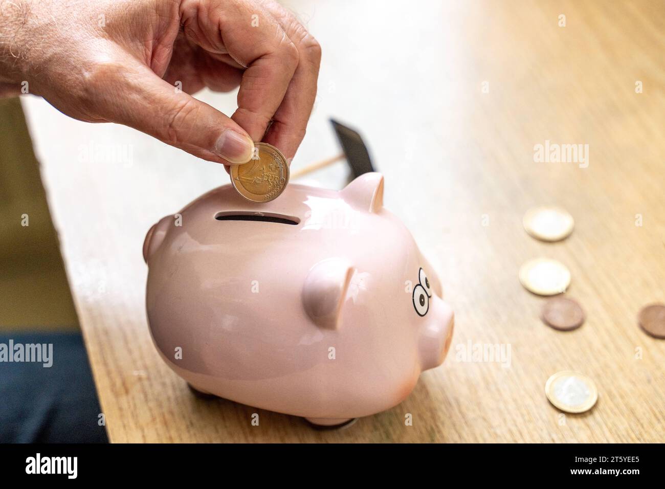 Augsburg, Bayern, Deutschland - 27 Oktober 2023: Ein alter Mann wirft Euro Geldmünzen in ein Sparschwein. Altersvorsorge Konzept *** An old man throws euro coins into a piggy bank. Retirement provision concept Credit: Imago/Alamy Live News Stock Photo