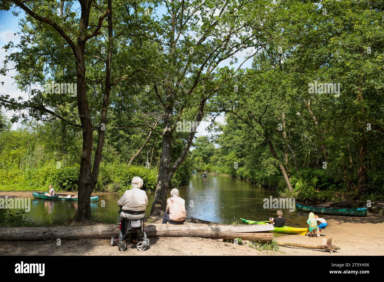 Two elderly people watching people passing in canoes at river Dommel, at nature reserve 'Malpie' in the Netherlands Stock Photo