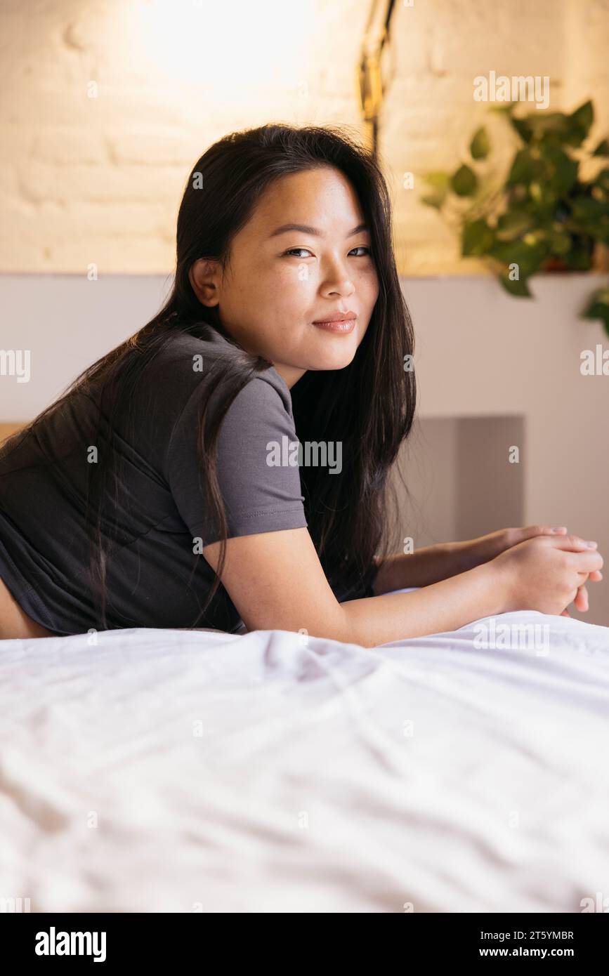 Portrait of young smiling woman lying on bed Stock Photo Alamy