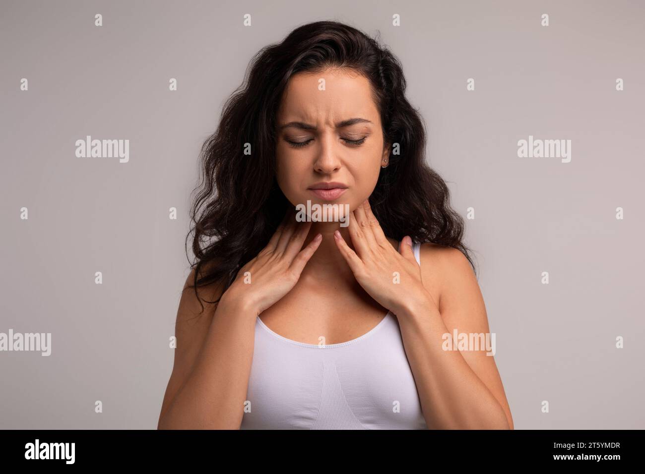 Unhappy millennial brunette woman touching her neck Stock Photo - Alamy