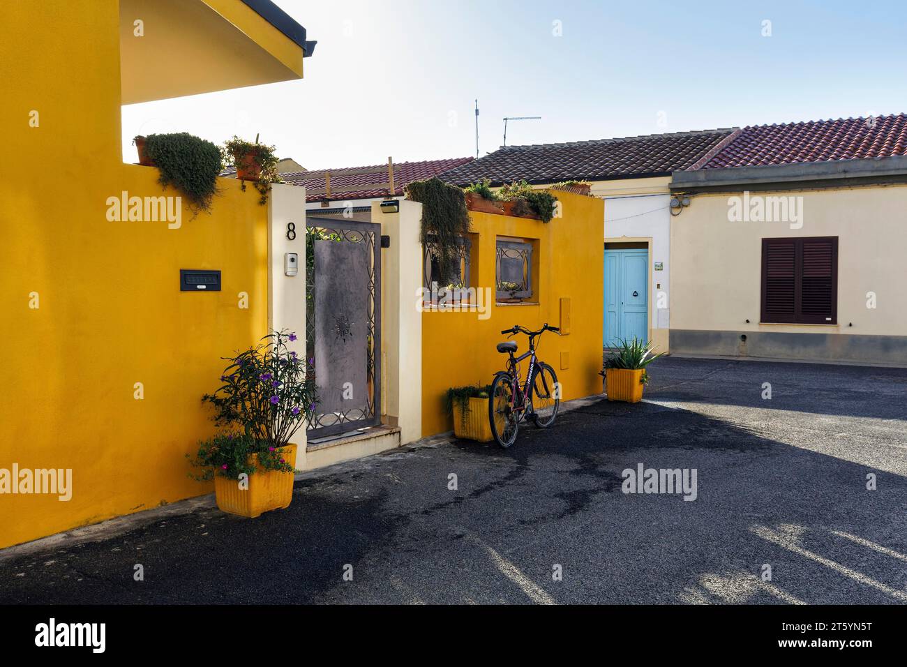 Potted plants and bicycle in front of a yellow house facade, Cabras, Oristano, Western Sardinia, Sardinia, Italy Stock Photo