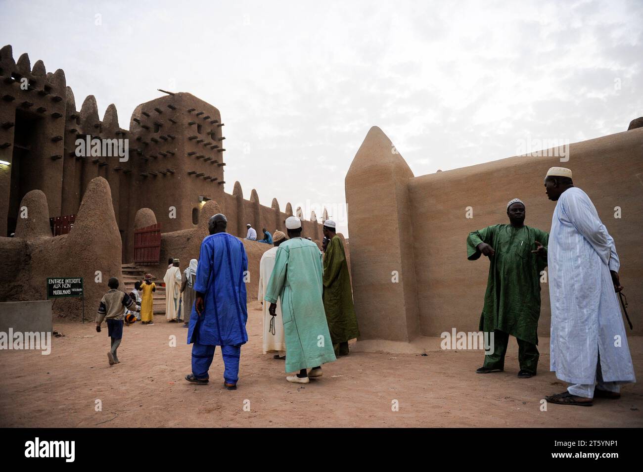 MALI, Djenne, Grand Mosque built from clay is a UNESCO world heritage site, muslim men going for prayer in the evening, wearing the traditional robe Boubou made from cotton or damask fabric Stock Photo