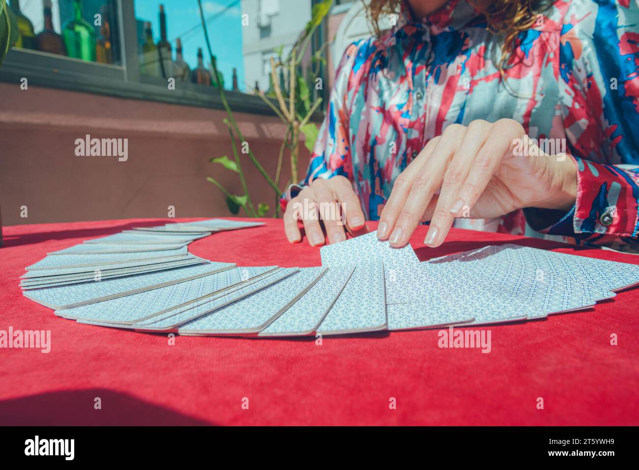 Caucasian Argentinian woman tarot reader, sitting taking card from fan-shaped deck on table, starting therapeutic tarot therapy. copy space. Stock Photo