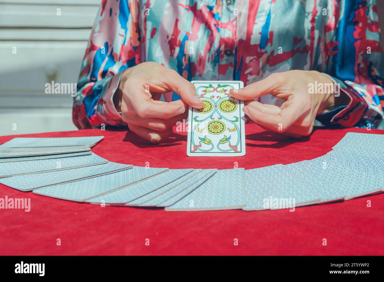 unrecognizable caucasian woman sitting at home showing tarot card on table, to her client during session, copy space. Stock Photo