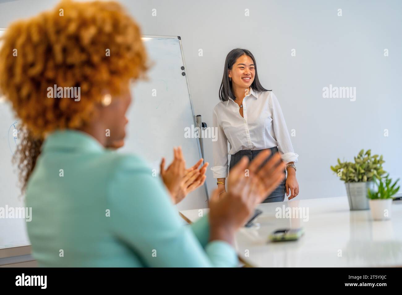 Chinese woman proud while people applauding her presentation in a coworking Stock Photo