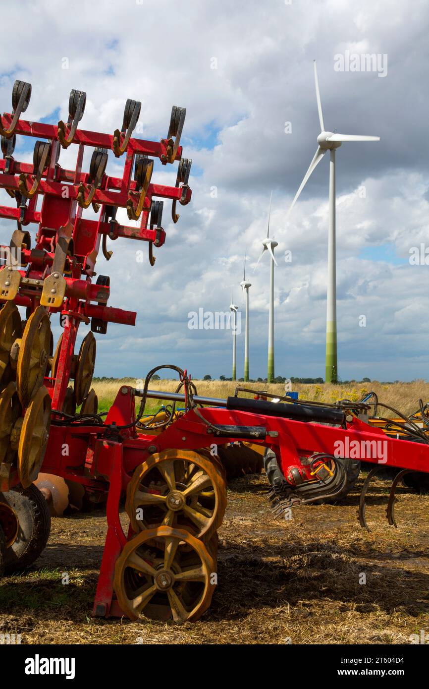 4 wind turbines on farmland at Conisholme Lincolnshire with agricultural machinery in the foreground. Stock Photo