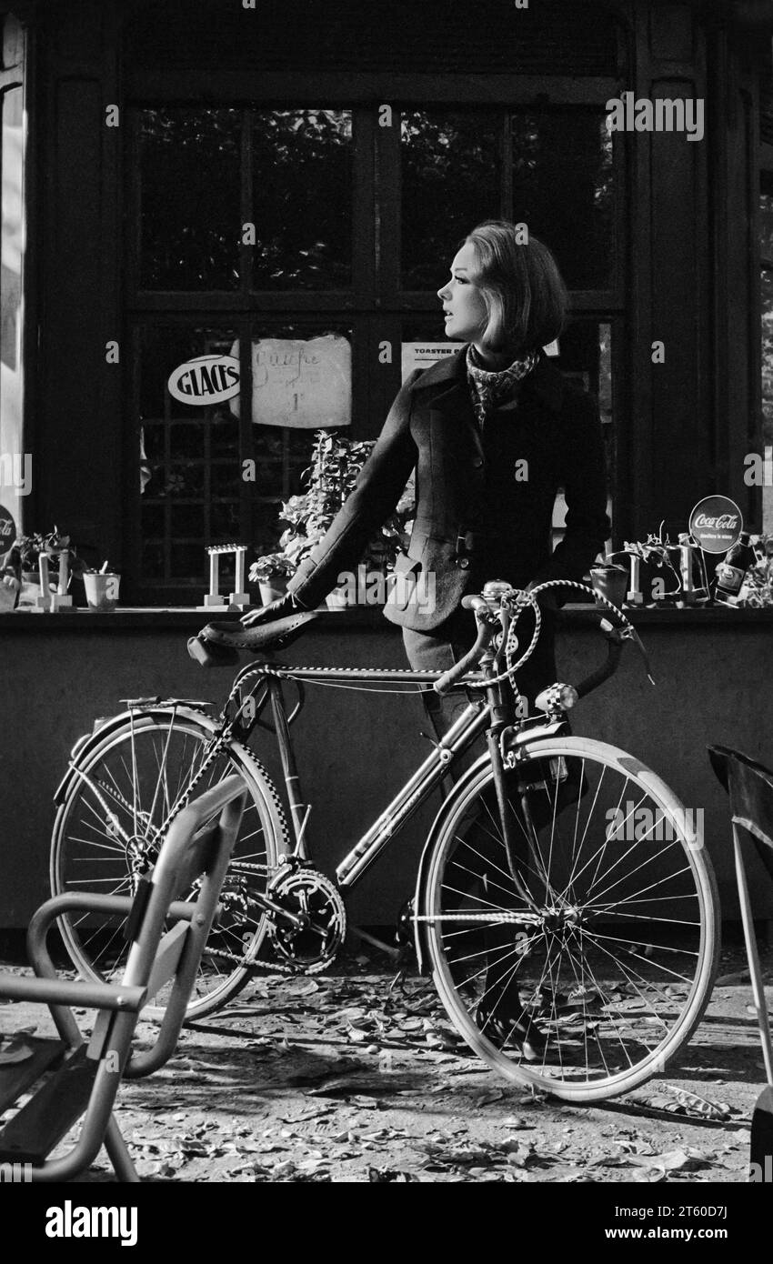 1960s, woman fashion model with bike by food and drink kiosk, Jardin des Tuileries garden, Paris, France, Europe, Stock Photo