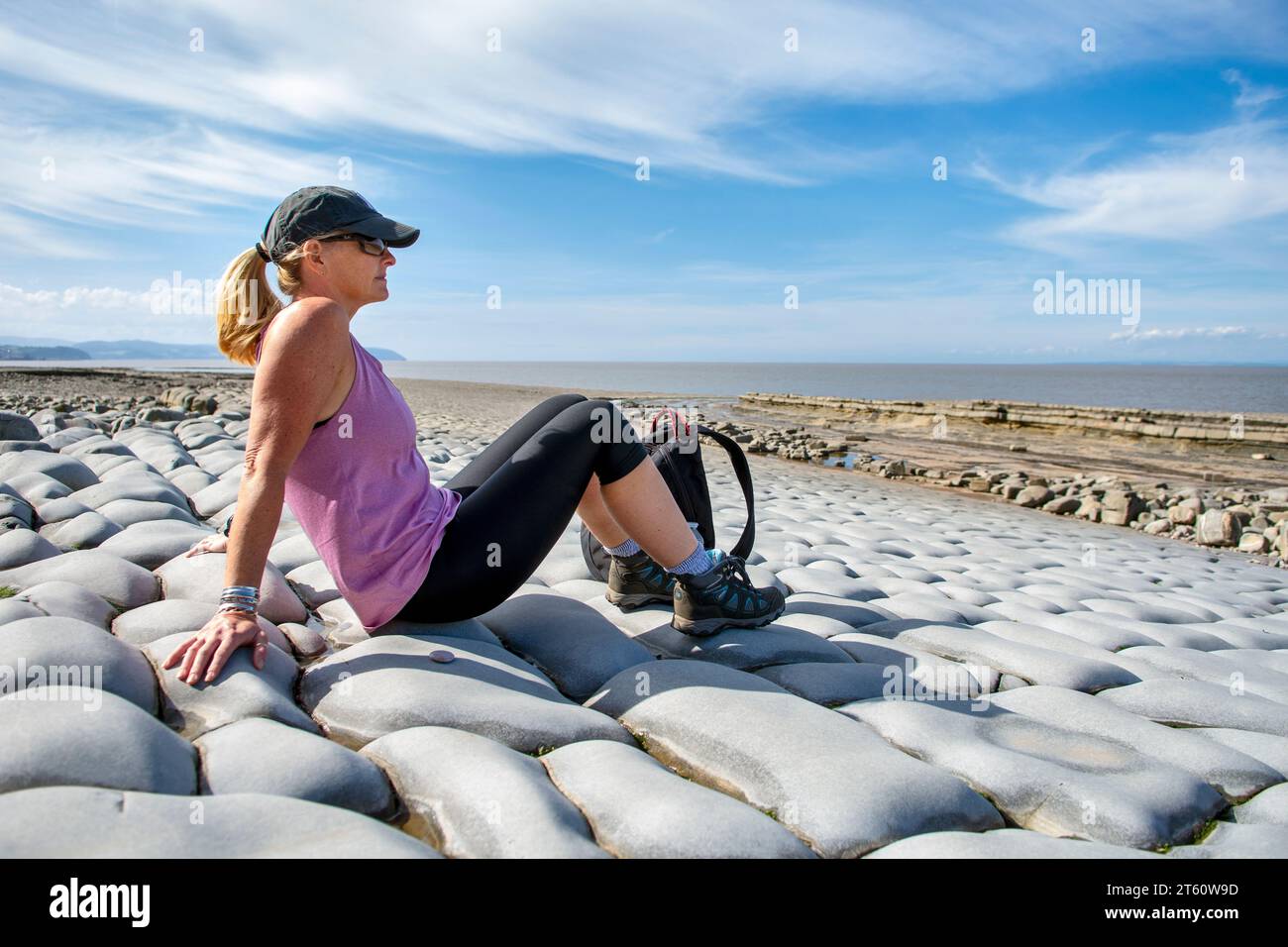 Woman on Kilve Beach and rocky Coastline, at Kilve, Quantocks, Somerset, UK on bright sunny day. Beach is well known for finding fossils. Stock Photo