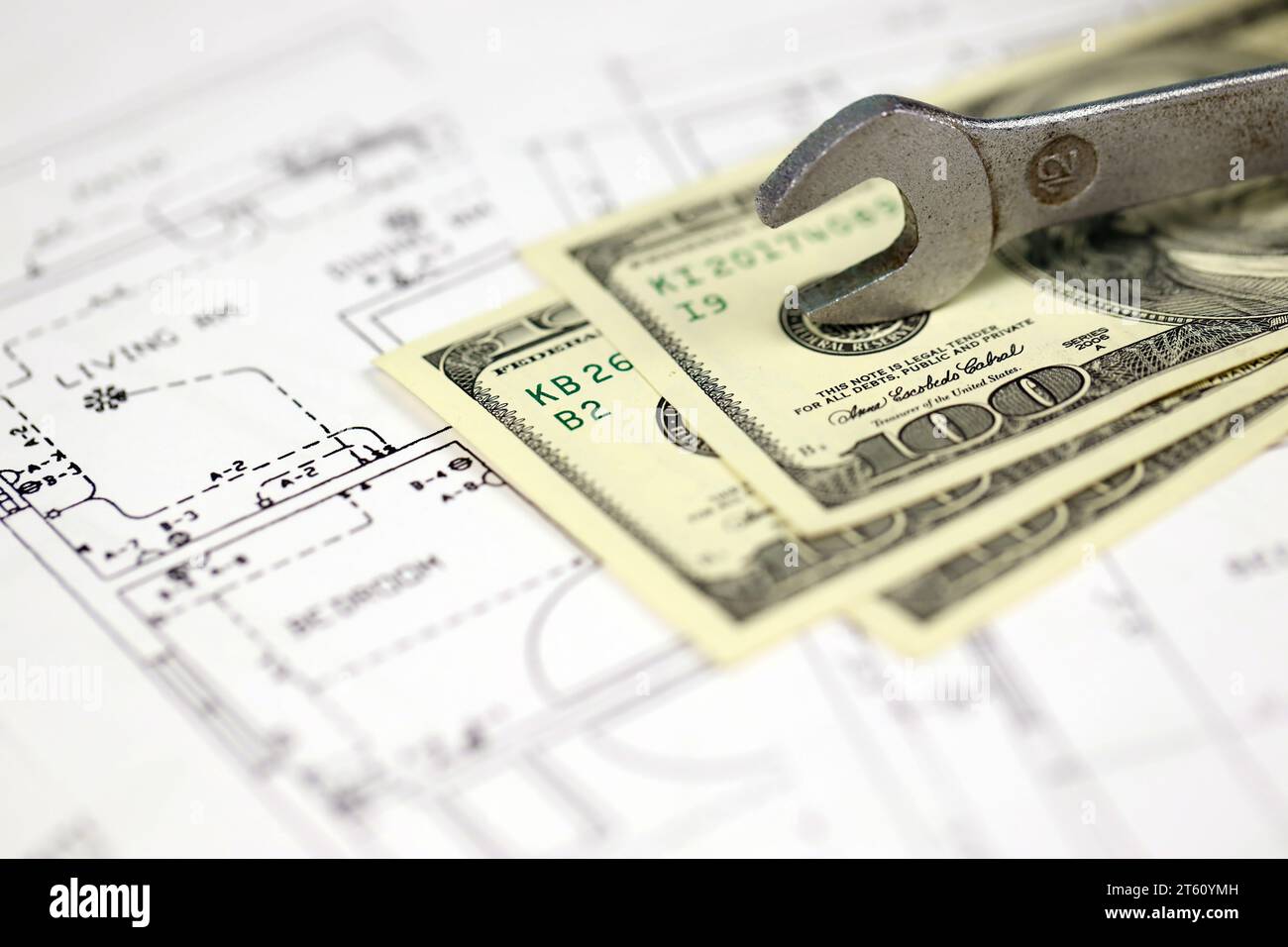 Spanner on top of money with blueprints of residential house plan