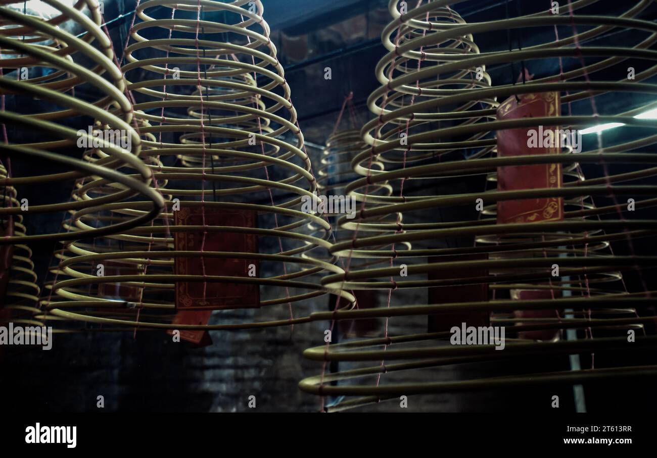 Multiple large yellow incense coils hanging in stacks from the Ceiling in a Chinese shrine. Large Bell Shaped Spiral Incense Coils, Focus and blur. Stock Photo