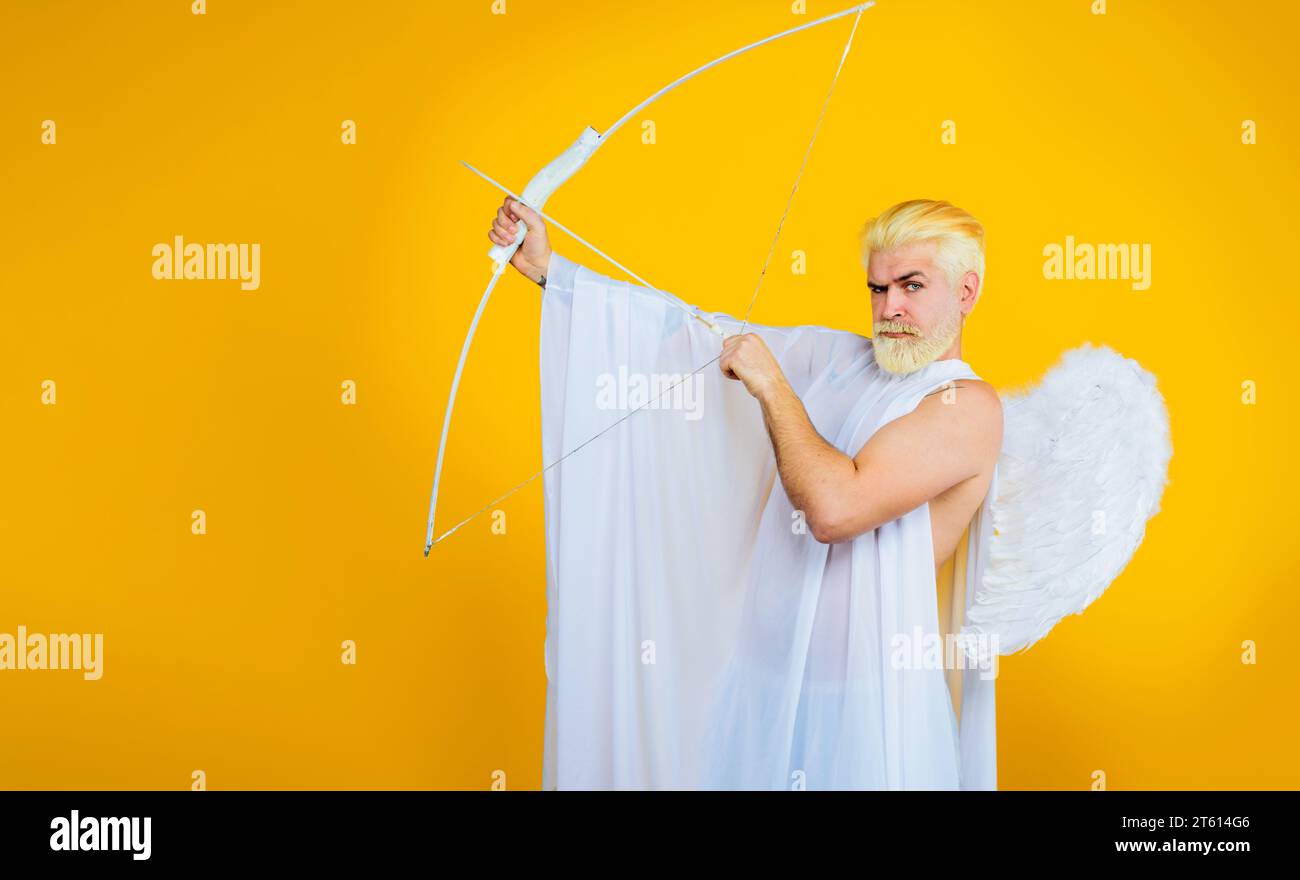 Valentines Day celebration. Arrow of love. Serious bearded man in white wings shooting love arrow. Valentines angel with white wings shoots love arrow Stock Photo