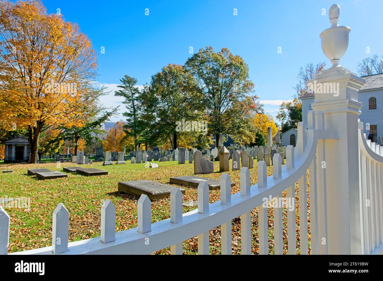 Cemetery at 1806 Old First Congregational church under fall leaf color in Bennington Vermont framed with ornate white picket fence Stock Photo