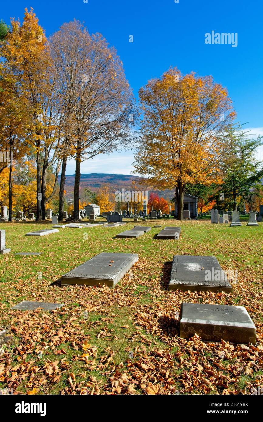 Tombstone lined 1806 Old First Congregational church cemetery distant hillside covered in autumn leave colors in Bennington Vermont Stock Photo
