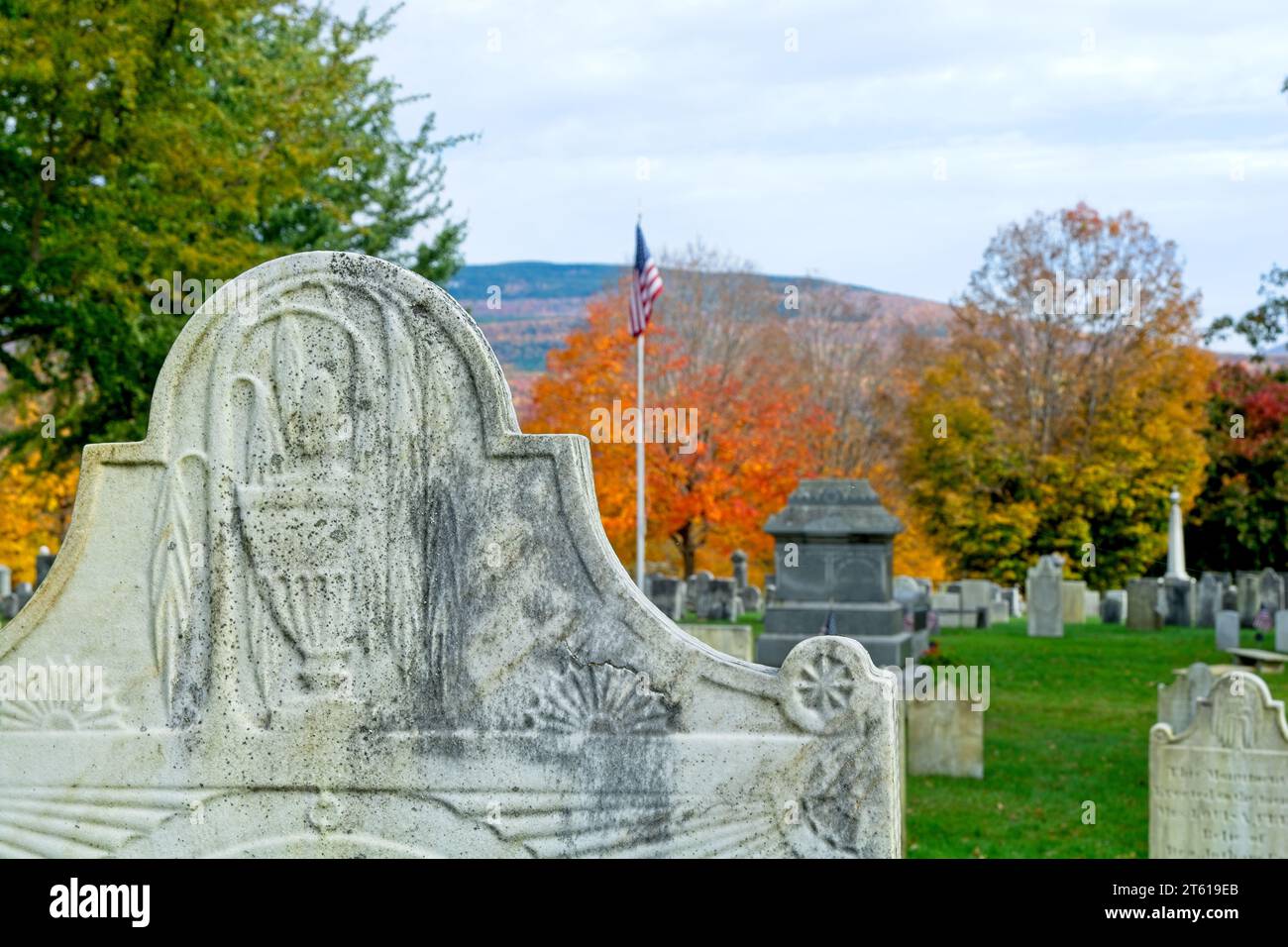 Close up of ornate headstone at 1806 Old First Congregational church cemetery distant hillside covered in autumn leave colors in Bennington Vermont Stock Photo