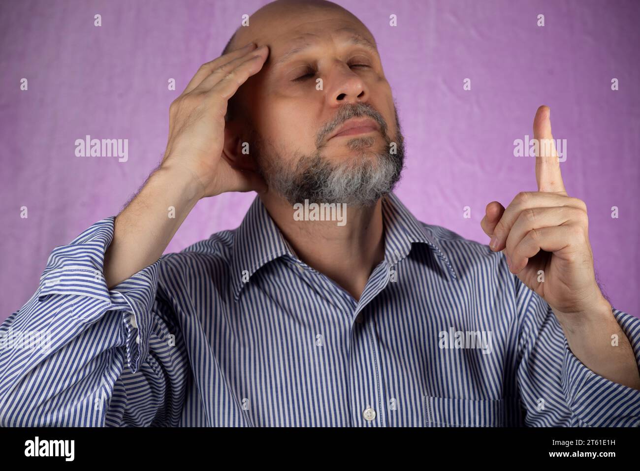 Man making sign with his hand against pink background. Stock Photo