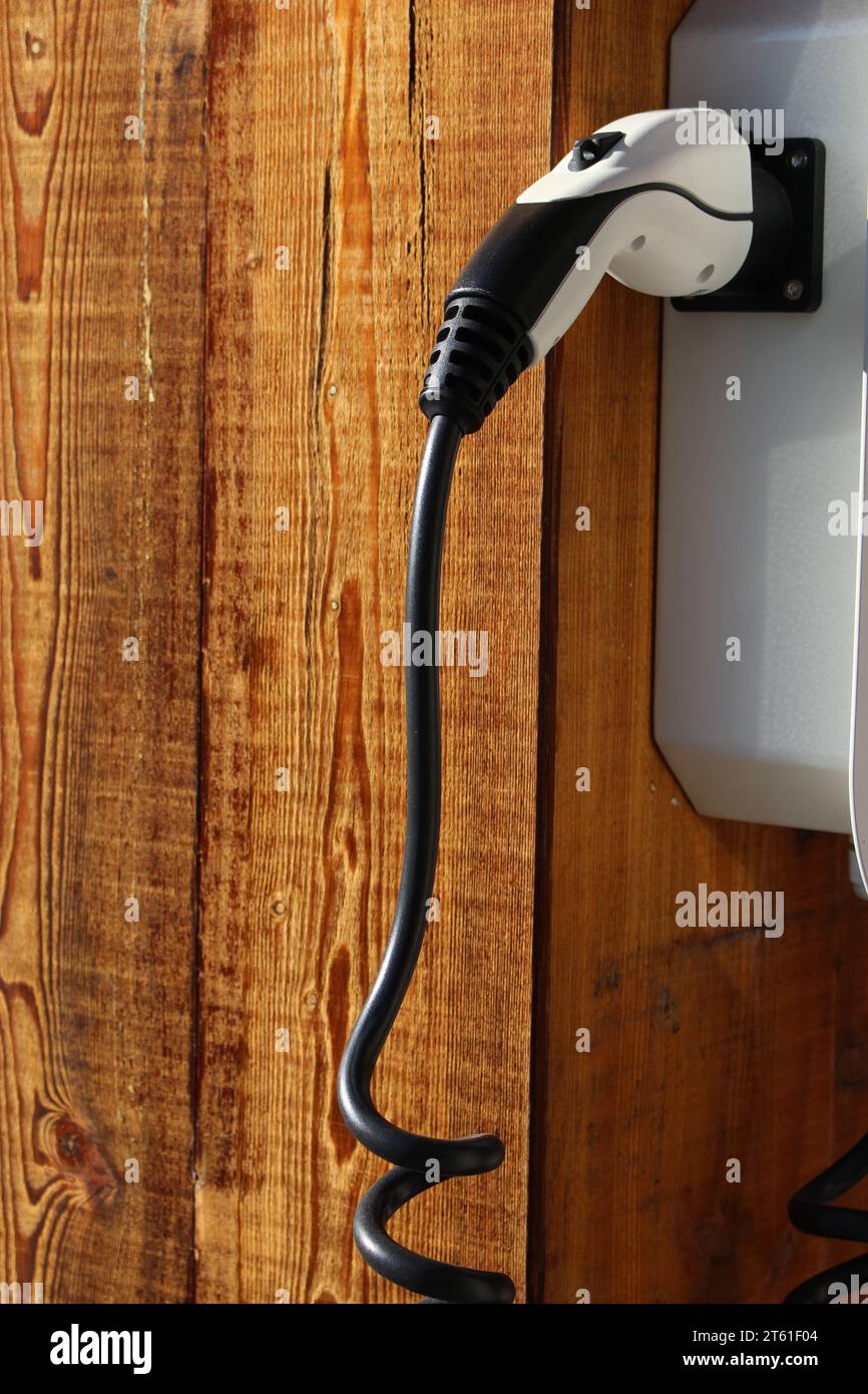 Electric car charger, electric car charging station in front of wooden beam in Verbier, Valais, Switzerland Stock Photo