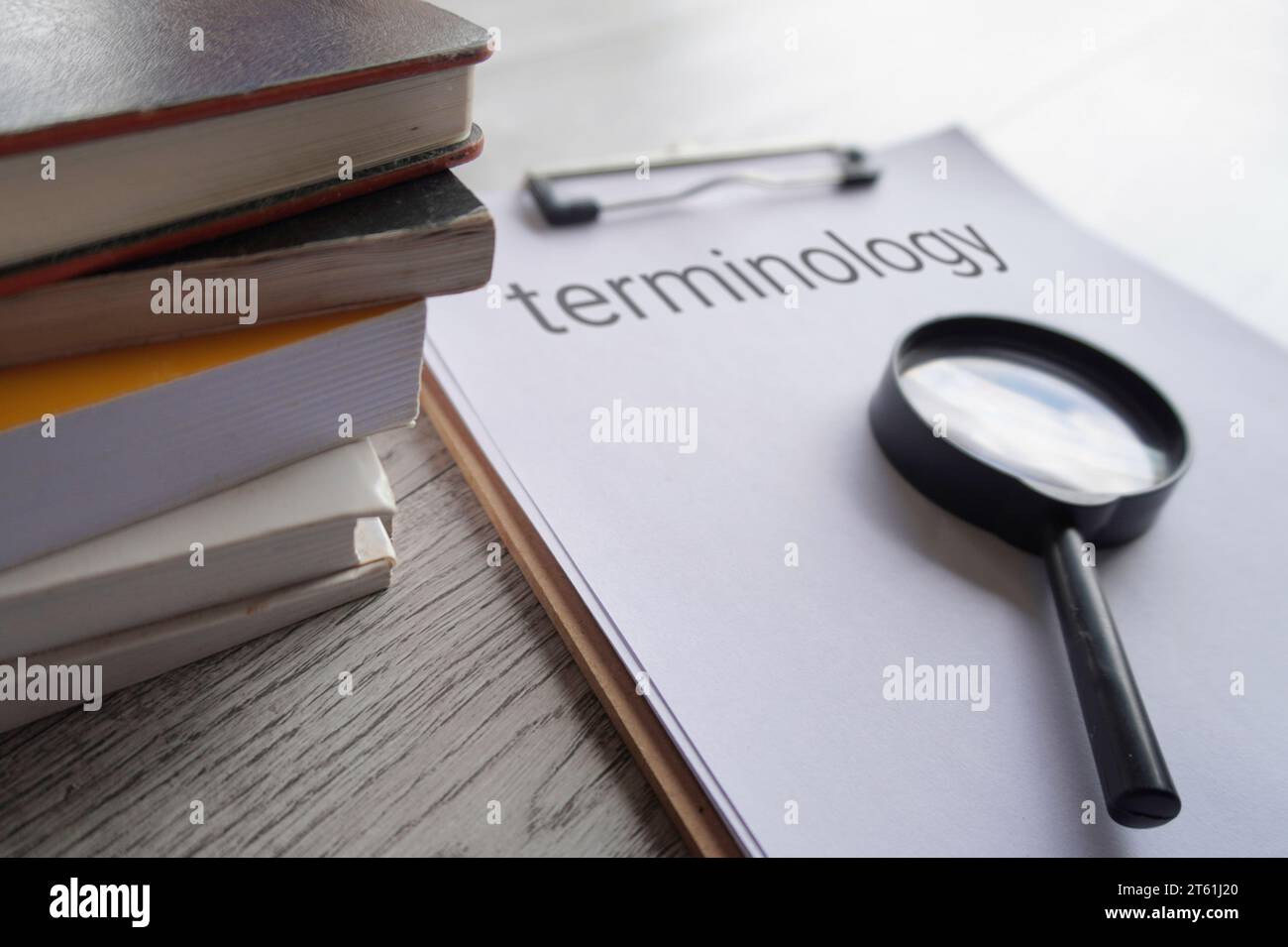 Closeup image of books, magnifying glass and paper clipboard with text TERMINOLOGY. Stock Photo