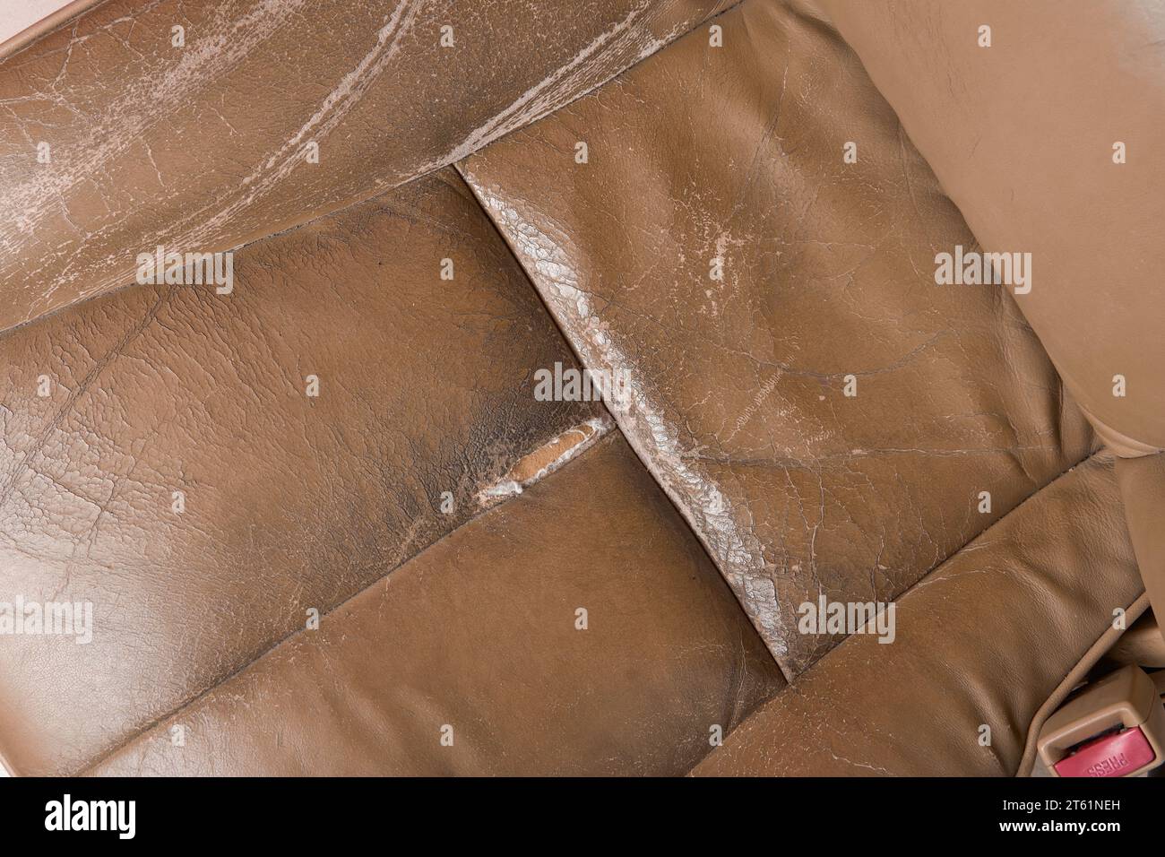 closeup of used worn and torn leather car seat, beige seat with wear