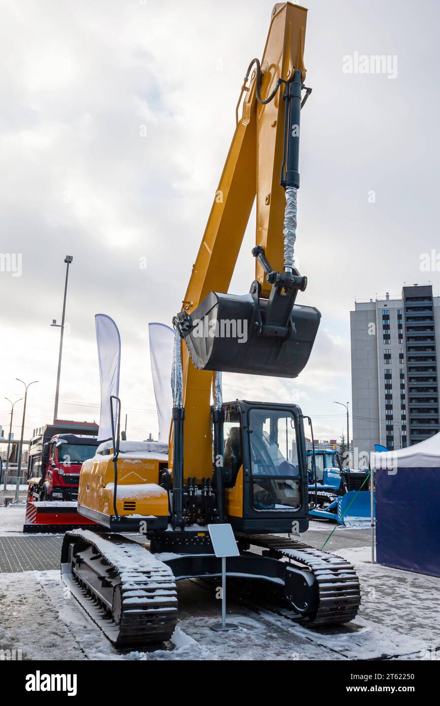 Modern crawler excavator with raised bucket at an industrial exhibition