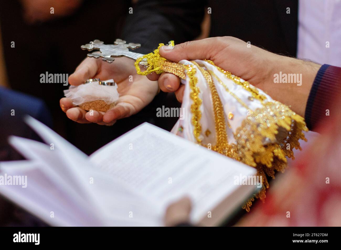 A close-up image of two hands in golden lace and a white shawl cradling an open Bible Stock Photo