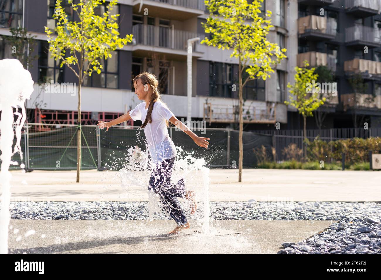 Happy kid playing in a fountain with water Stock Photo - Alamy