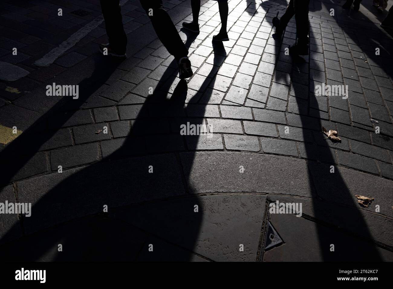 City workers shadows across a central London pavement as the darkness of a possible recession and unemployment looms, London, UK Stock Photo