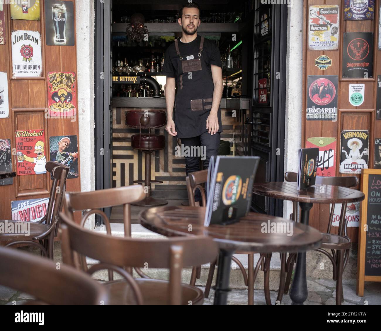 Montenegro, Apr 12, 2023: A waiter leaning against the bar dozes in a currently empty pub in Kotor Old Town Stock Photo
