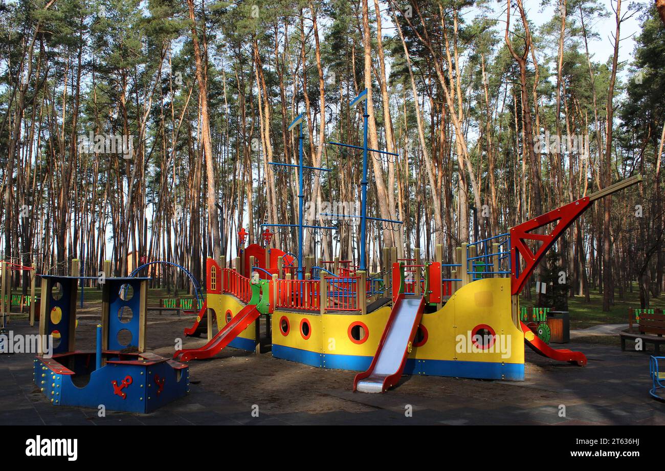 Sandbox, multi-colored slides and swings on the playground for active games in the green area Stock Photo