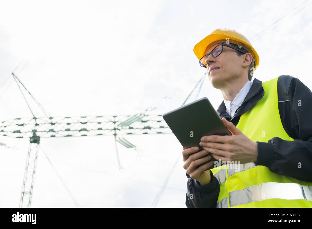 Engineer with digital tablet on a background of power line tower. Stock Photo