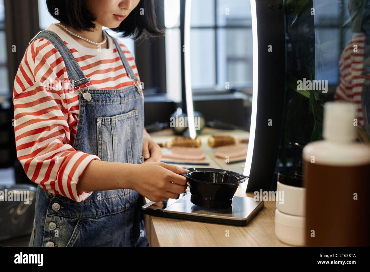 Side view closeup of young hairstylist mixing hair dye and weighing