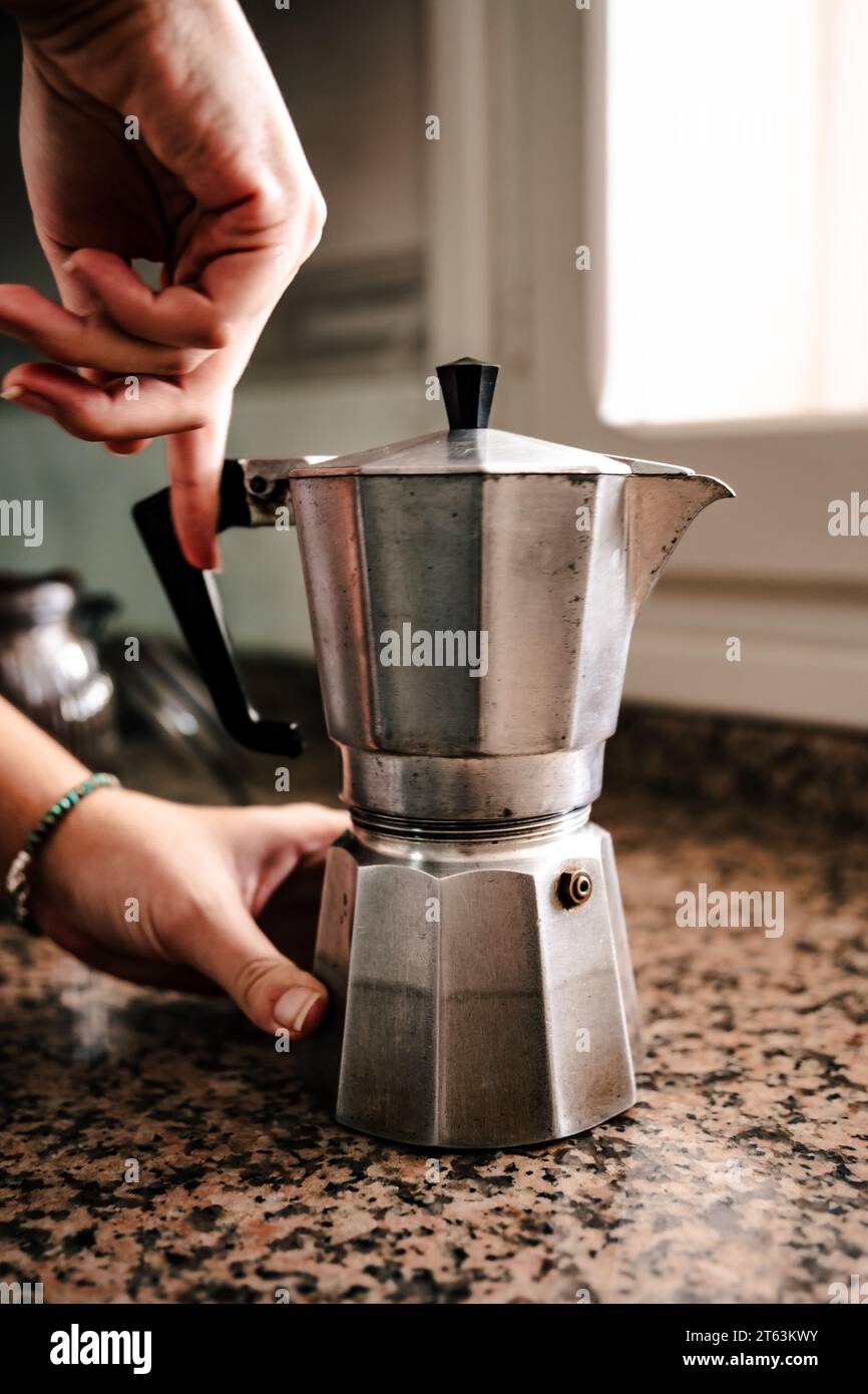 https://c8.alamy.com/comp/2T63KWY/anonymous-young-individual-hands-expertly-assembling-a-stainless-steel-stovetop-espresso-maker-on-a-speckled-countertop-with-ambient-light-filtering-t-2T63KWY.jpg