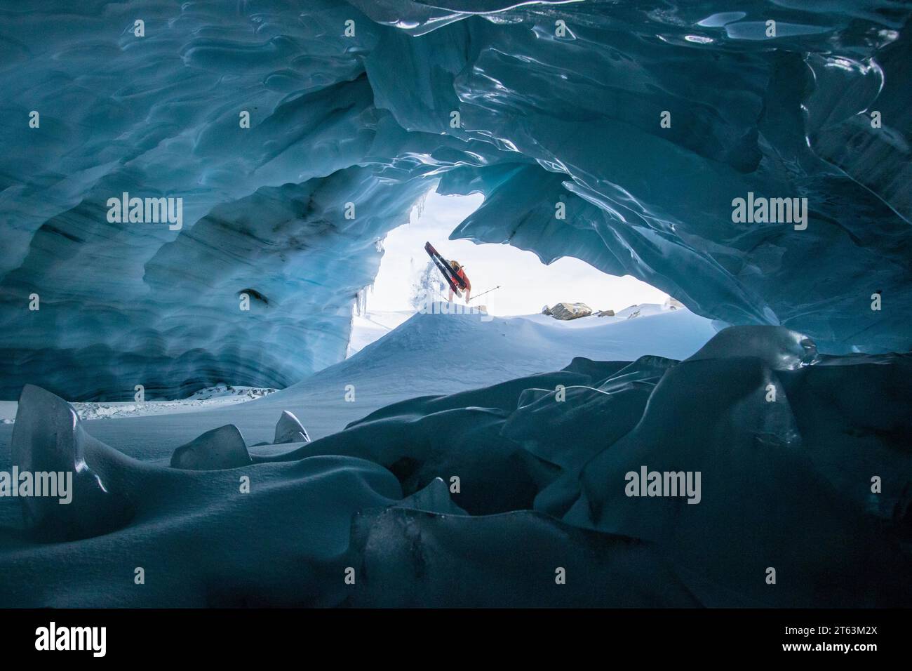 Unrecognizable skier with ski poles walking in cave at snowy mountain while exploring during vacation at Swiss Alps Stock Photo