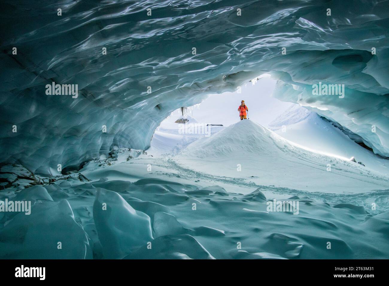 Skier with ski poles walking in cave at snowy mountain while exploring during vacation at Swiss Alps Stock Photo