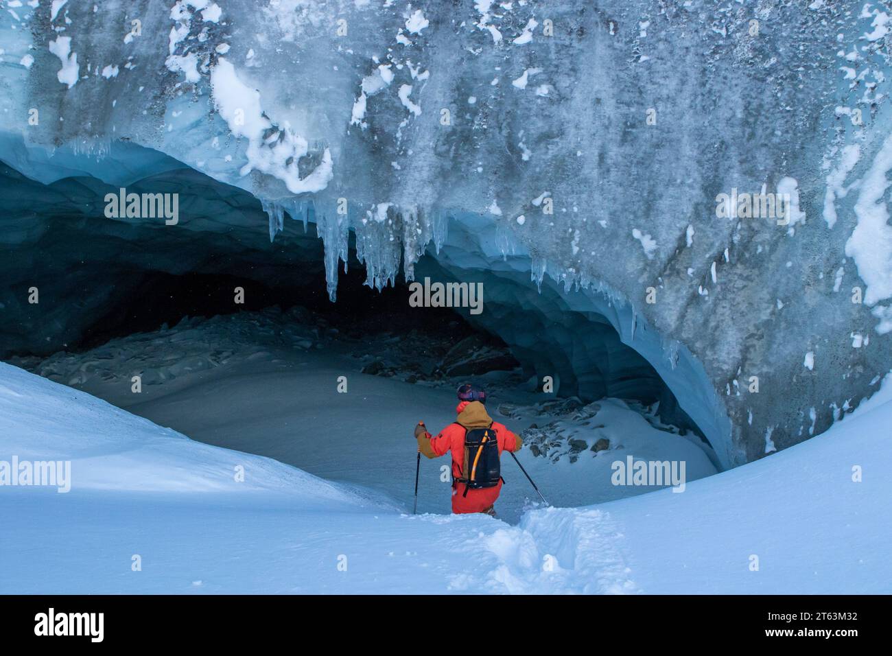 Back view of unrecognizable skier with ski poles walking in cave at snowy mountain while exploring during vacation at Swiss Alps Stock Photo