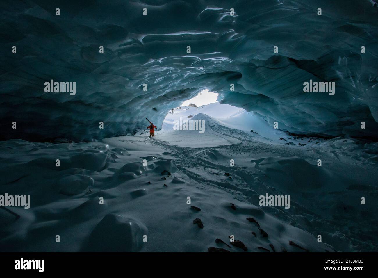 Back view of unrecognizable skier with ski poles walking in cave at snowy mountain while exploring during vacation at Swiss Alps Stock Photo